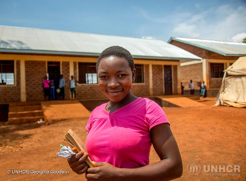 Fourteen-year-old Congolese student, Joceline, carries her French and Kirundi language books to class at Hope Secondary School in Nyarugusu refugee camp, Tanzania ; Nyarugusu refugee camp, created in 1996 and situated in Tanzania’s western province of Kigoma, hosts around 150,000 refugees. Originally accommodating Congolese refugees fleeing civil war, the camp now also hosts some 65,000 Burundians who have fled political unrest. A massive funding shortfall means that, in western Tanzania’s refugee camps – including nearby Nduta and Mtendeli – UNHCR has not been able to construct the required number of classrooms at the camps’ schools. With just 193 classrooms for 9,650 children, over 70 per cent of students study outdoors. Around 625 additional classrooms are needed, at a cost of $12,000 each. Additional costs for teacher salaries and exams, and desperately needed funding for shelter and other basic needs mean living conditions are tough. Funding for Congolese and Burundian refugees are raised separately. UNHCR’s appeal for $217 million to assist Burundian refugees in Tanzania is grossly underfunded, with just 7 per cent of funding received (as of November 2017.)