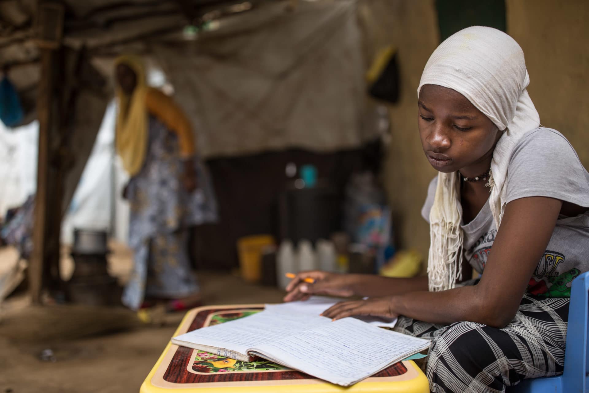 A young refugee student studies at her home