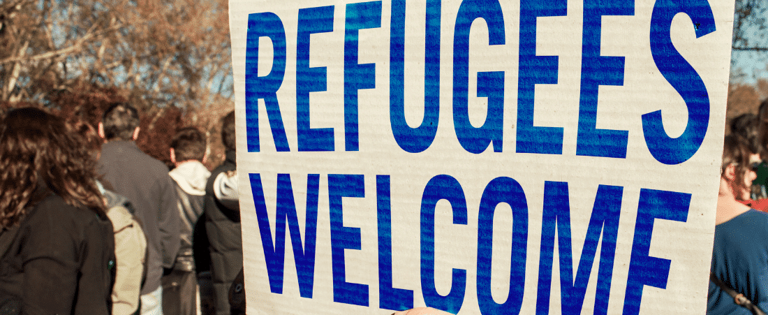 A sign reads Refugees Welcome