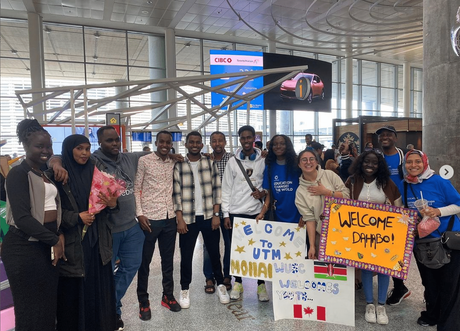 A group of post-secondary students hold signs at the Toronto airport to welcome newly arriving students through the Student Refugee Program.