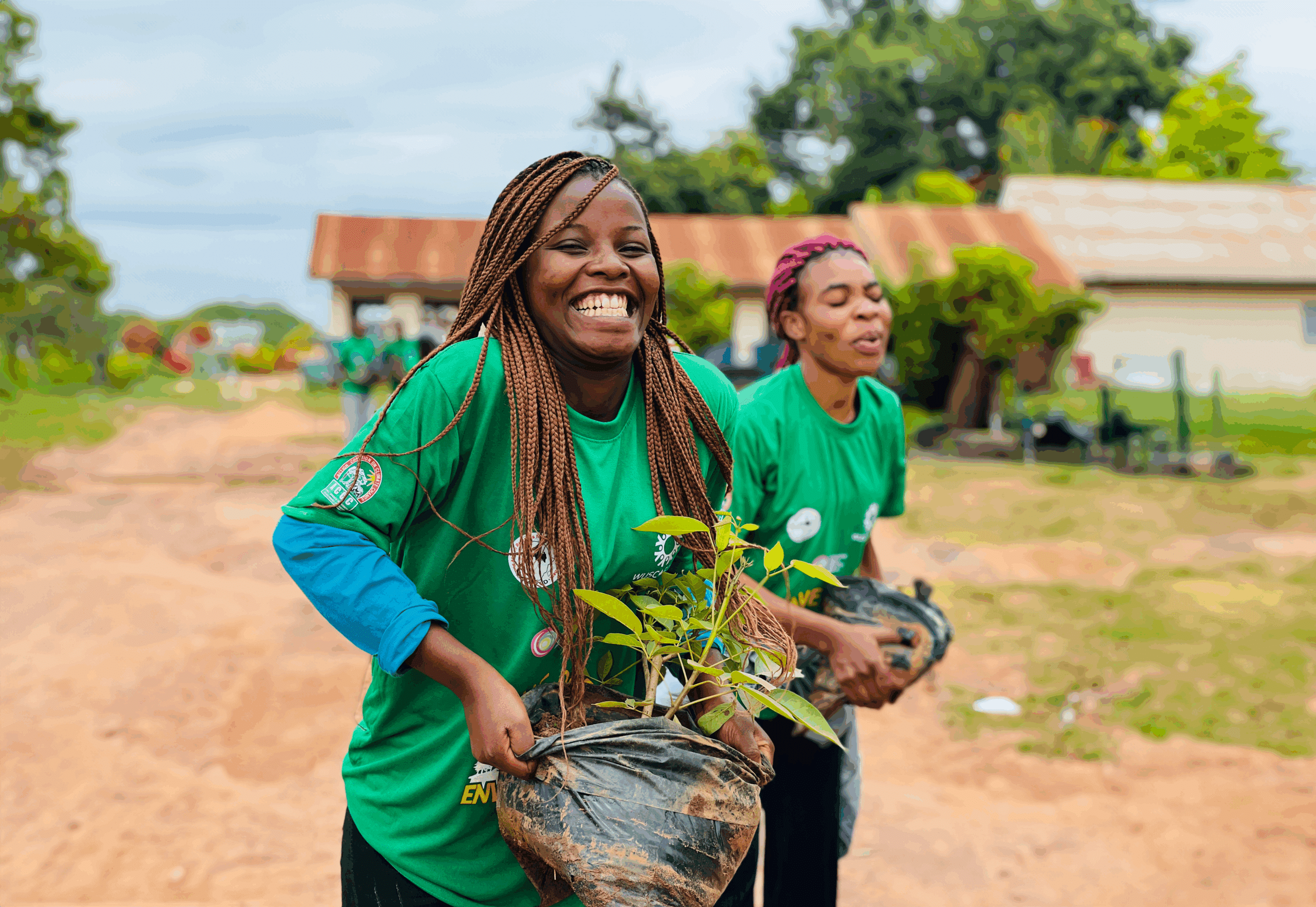 Two young women carry trees for planting