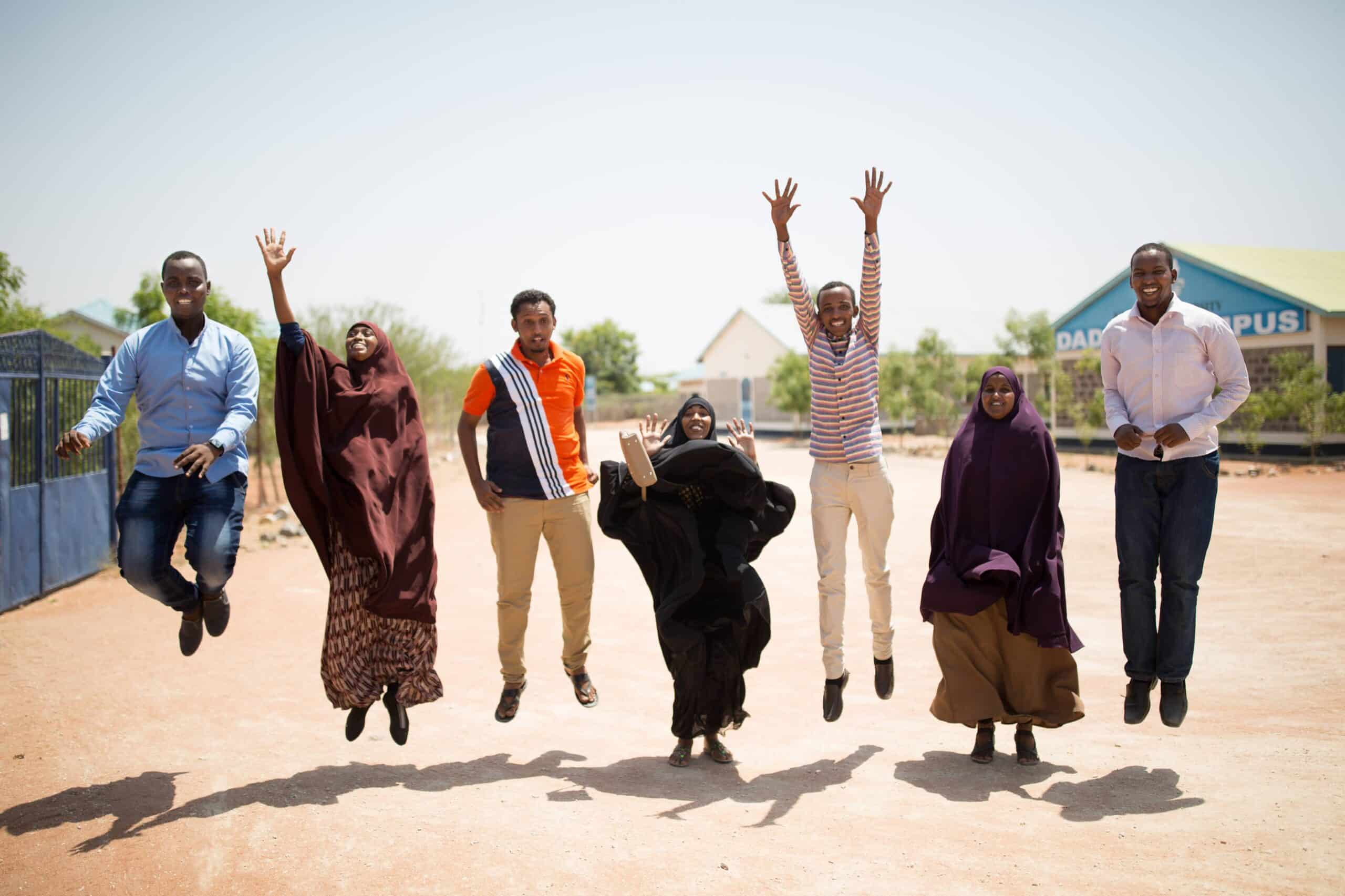 A group of young refugees jumping in the air.