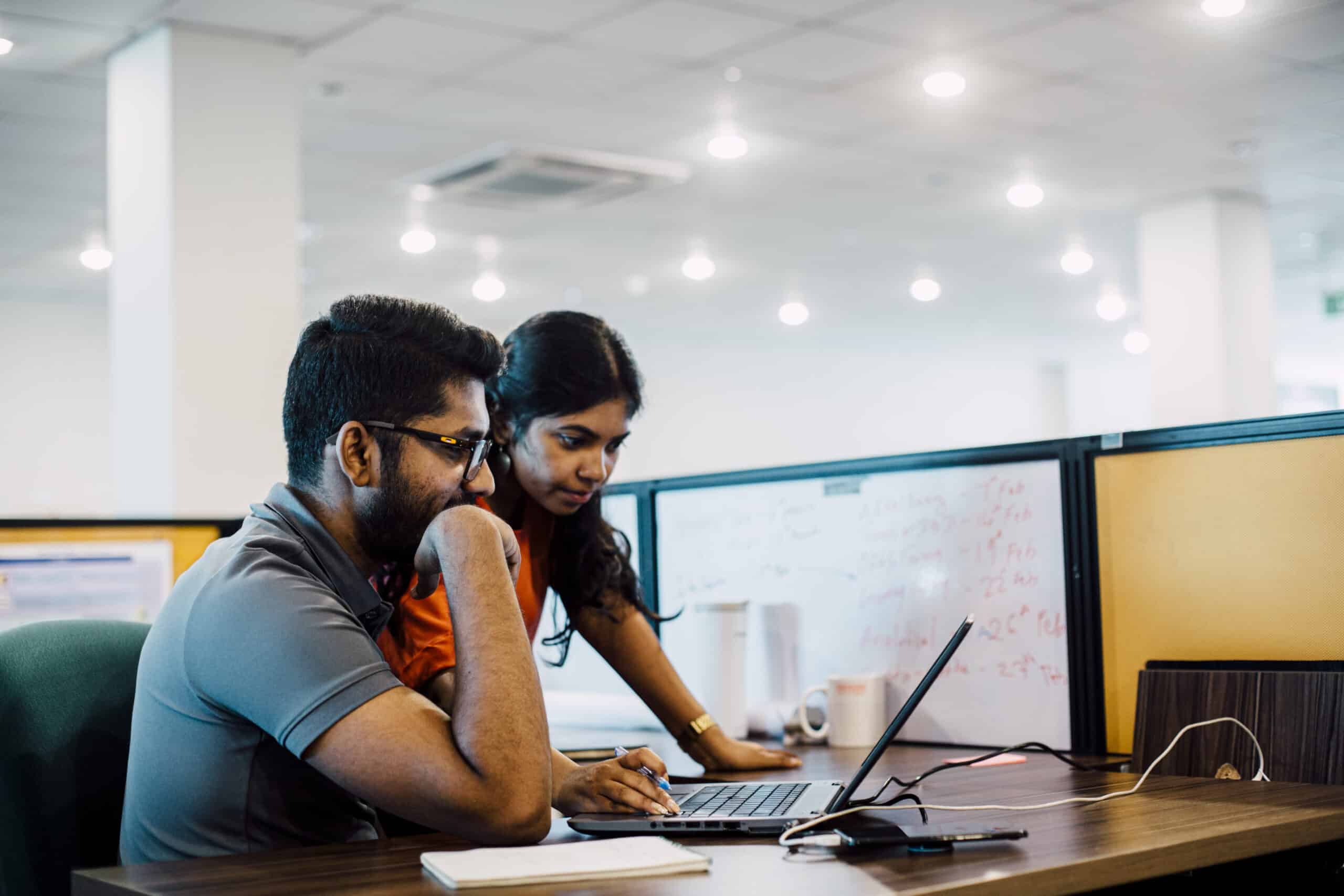 Two young colleagues review their work on a laptop together