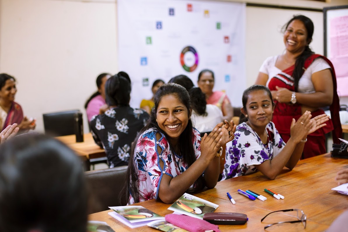 Young women participating in a skills building workshop in Sri Lanka smile as they applaud the workshop facilitator.